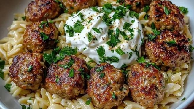 Greek meatballs served with lemon orzo and creamy feta sauce on a plate Greek meatballs served with lemon orzo and creamy feta sauce on a plate