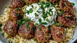 Greek meatballs served with lemon orzo and creamy feta sauce on a plate